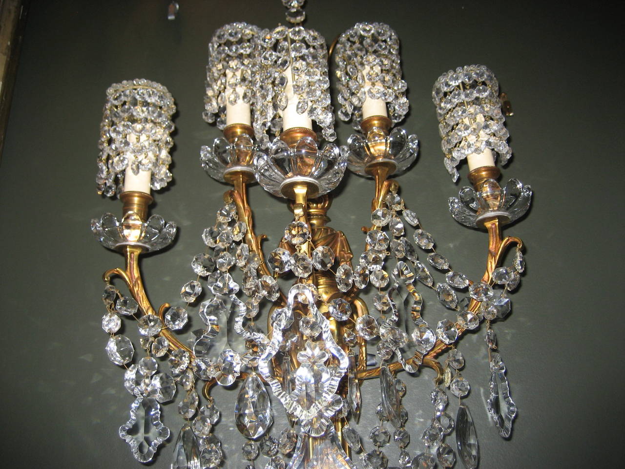 A large antique French Louis XVI style gilt bronze and cut crystal multi light wall sconce of Fine detail embellished with cut crystal chains, prisms and unusual cut crystal shades.