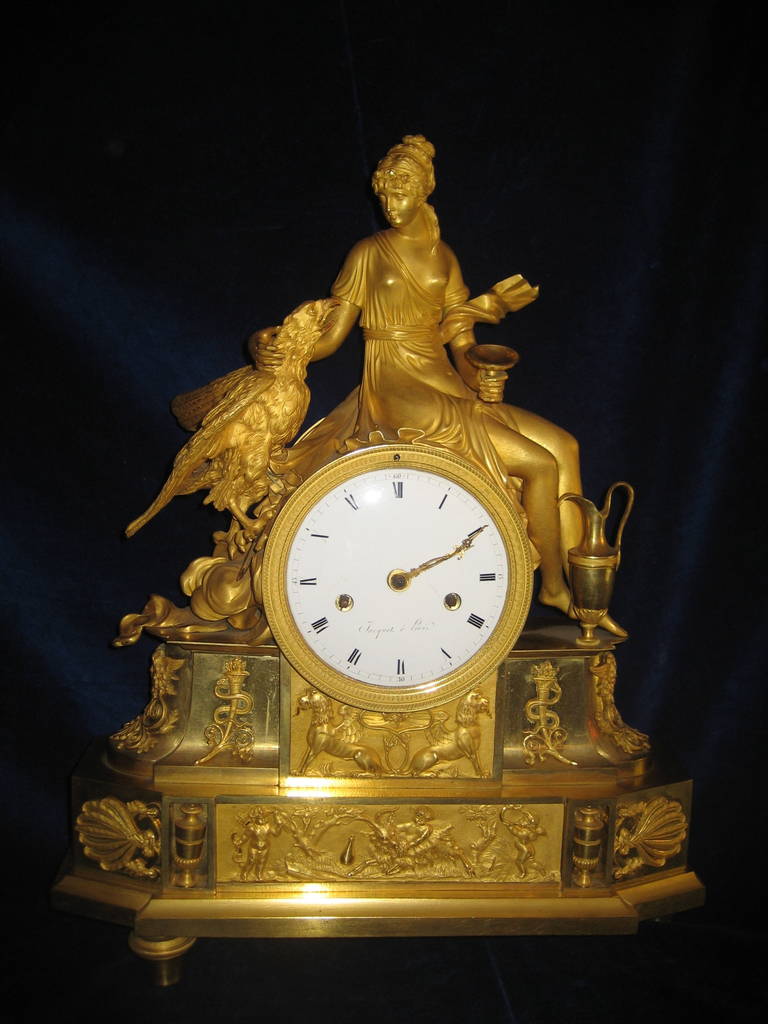 An Exquisite Antique French Period Empire Neoclassical gilt bronze figural clock embellished with figure of a neoclassical woman and bird.