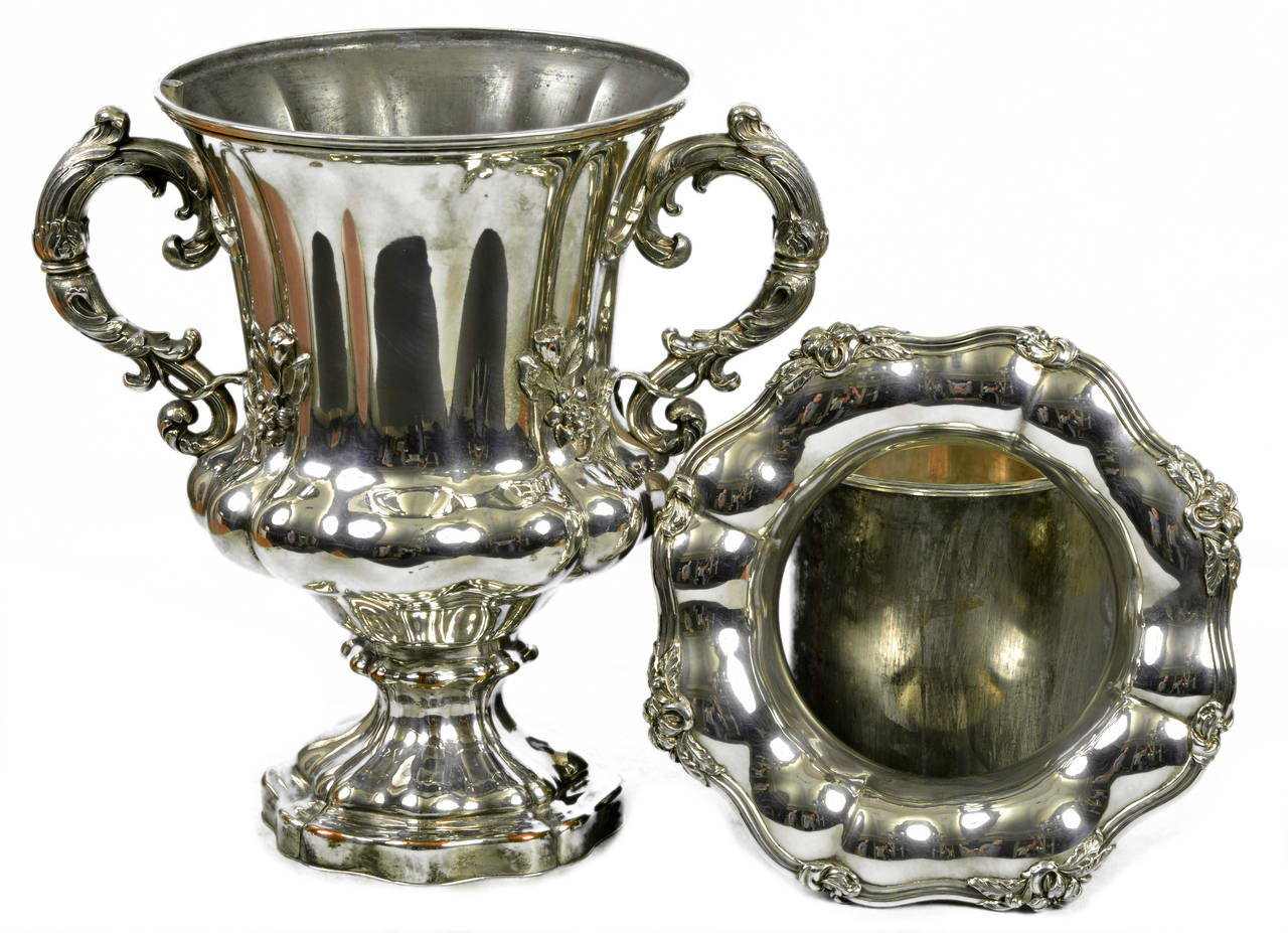 A fine silver plated wine cooler, mid-19th century; unmarked
Also known as ice bucket or ice pail our cooler has a cast lobed urn raised on spreading conforming foot, with a removable cylinder liner and removable scalloped rim with applied floral