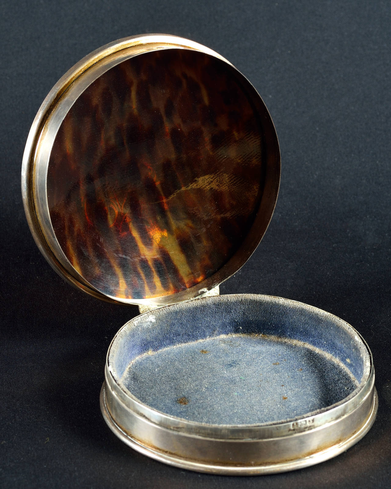 Sterling silver and tortoiseshell jewellery box.
Circular shape and hinged cover inset with tortoiseshell plaque inlaid with silver ornaments.
Velvet lined interior.
Fully hallmarked.
England, Birmingham, 1920.
Diameter 10.8 cm (4