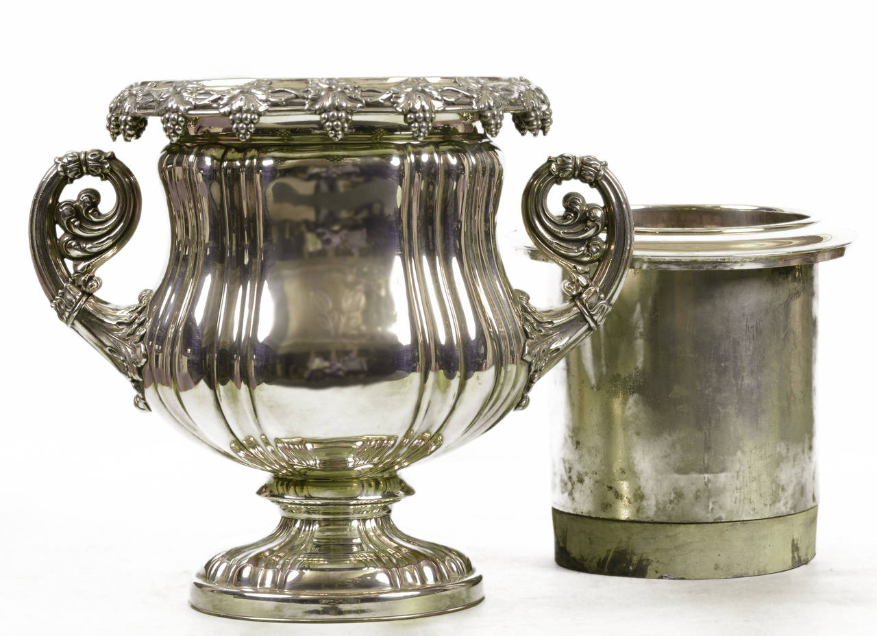 Champagne bucket or wine cooler.
Fluted body with commemorative inscription dedicated to H.J. O’Connell, past master of the hunt 1955-1977, at The Lake of Two Mountains Hunt Club.
Volute-shaped handles.
Rim decorated with well-cast clusters of