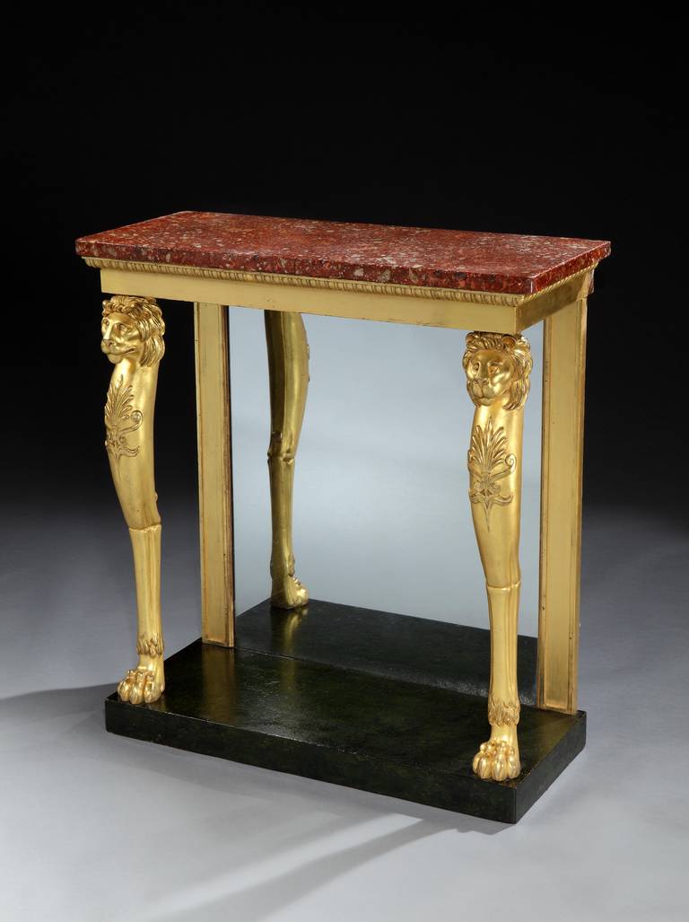 A fine Regency giltwood console table the original red scagolia top above an egg and dart frieze, resting on lions monopodia legs terminating in paw feet, on a faux marble plate-form base.

English, circa 1810.