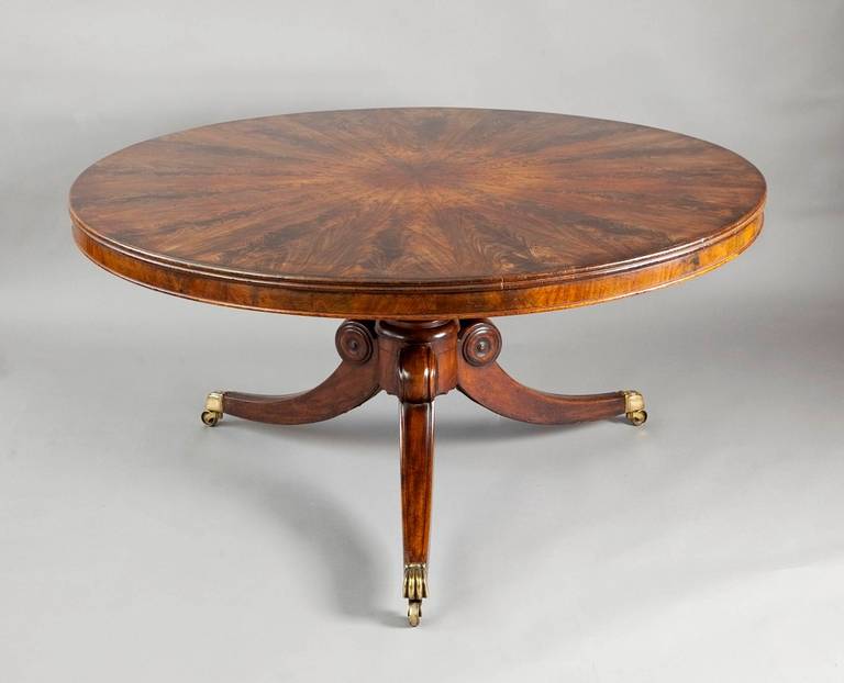 A large Irish George IV centre table, the top veneered in twenty four richly figured segments of finest mahogany, with double reeded edge, above a mahogany frieze, resting on a turned and fluted three splay pedestal, with reeded brass castors.