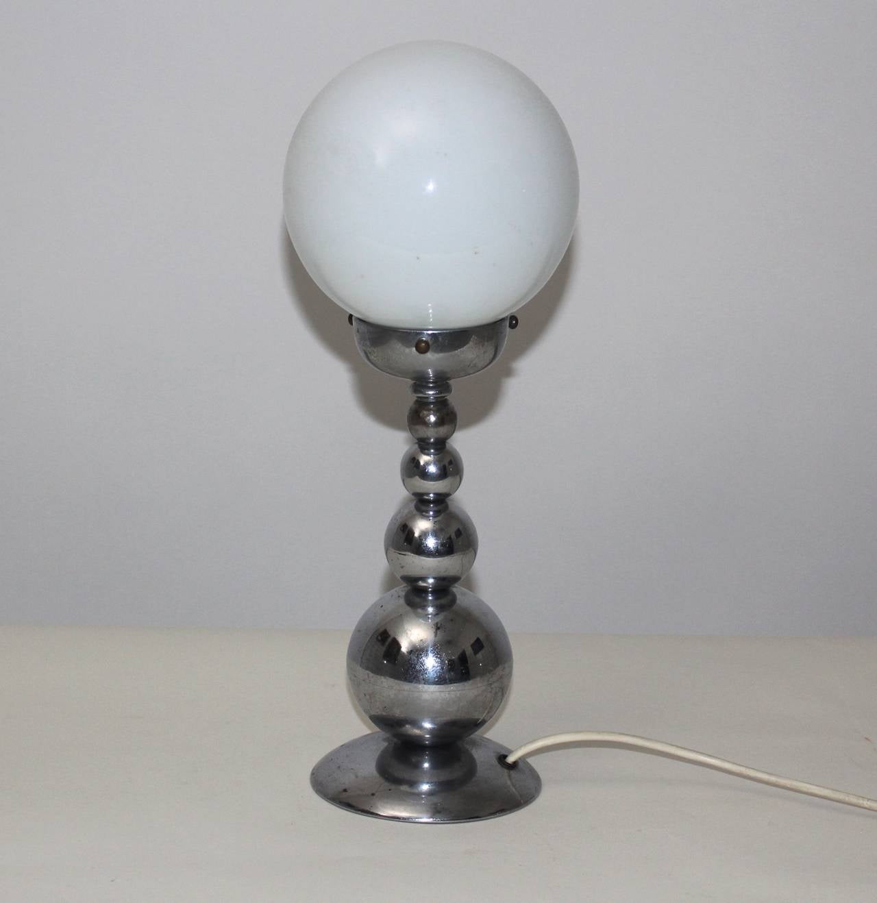 A Mid Century Century vintage chromed table lamp, which shows a lollipop base with four chromed metal globes and a white milk glass shade.

The vintage condition is very good.
All measures are approximate.