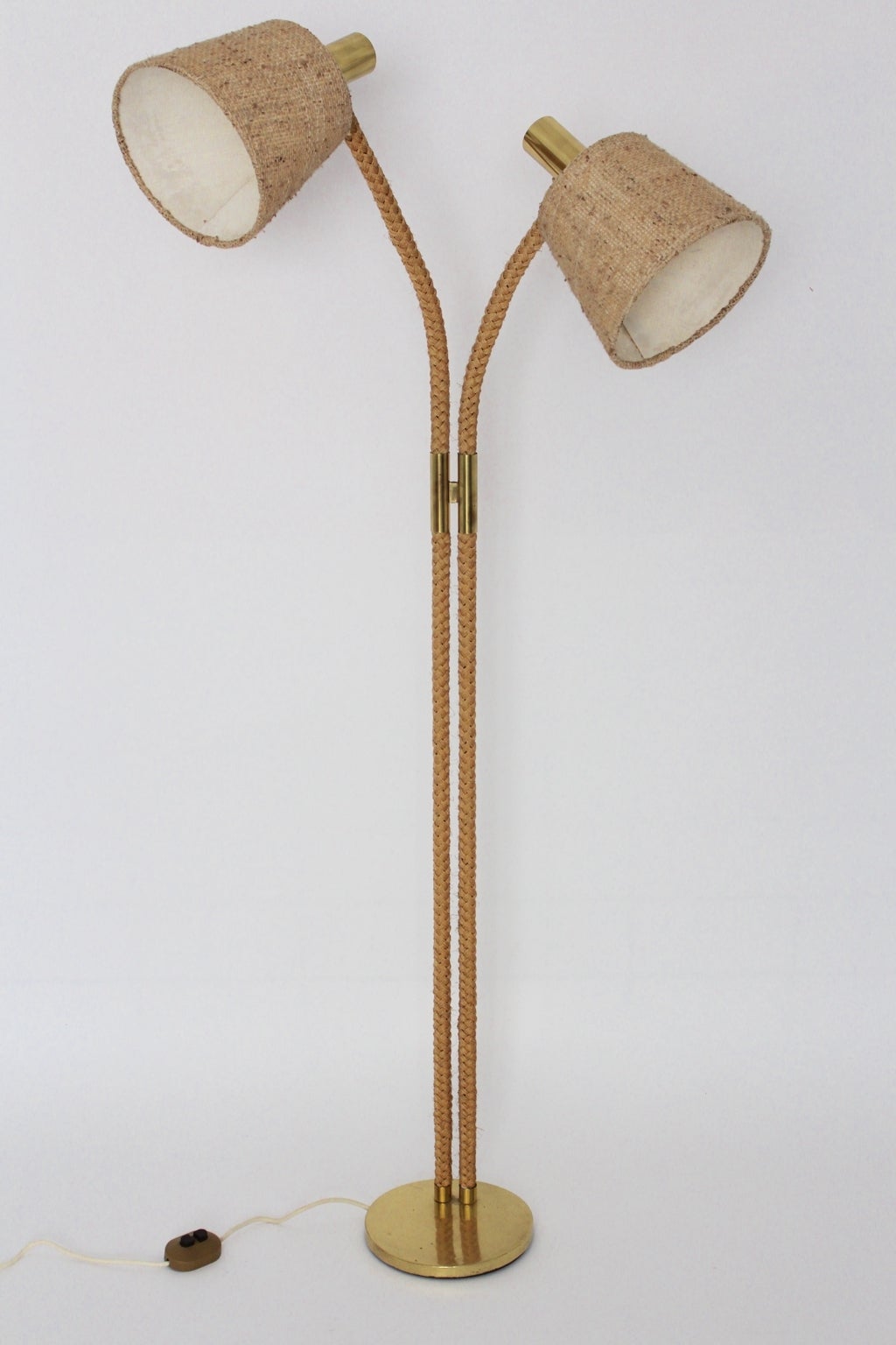 This presented Mid-Century Modern floor lamp in the style of Adrien Audoux et Frida Minet, 1960s is taped with twisted cords and shows also brassed details.
Also the two shades, which are formed like a baskets, are covered with natural canvas and
