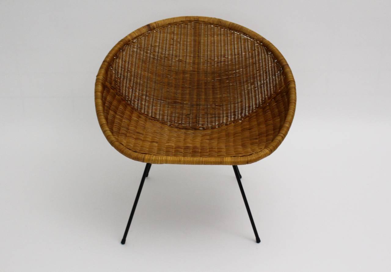 Mid century modern vintage woven rattan club chair designed and produced in France 1950s.
The base was made out of a black lacquered wire steel base with rubber feet, while the comfortable seat shell was made of woven rattan.
The club chair is