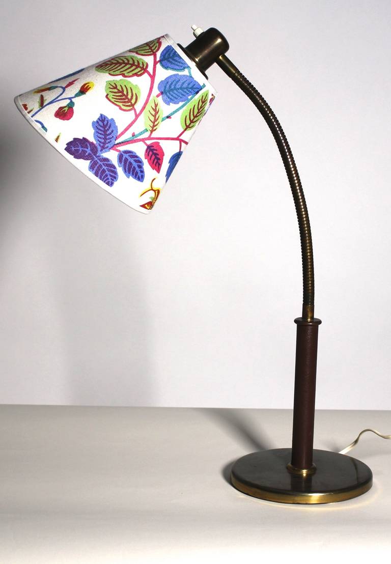 Gorgeous Viennese table lamp designed by Josef Frank and executed by J.T.Kalmar.

The table lamp has an adjustable arm and the handle is taped with leather to the half.
The shade is newly covered with Josef Frank fabric.
One bulb E