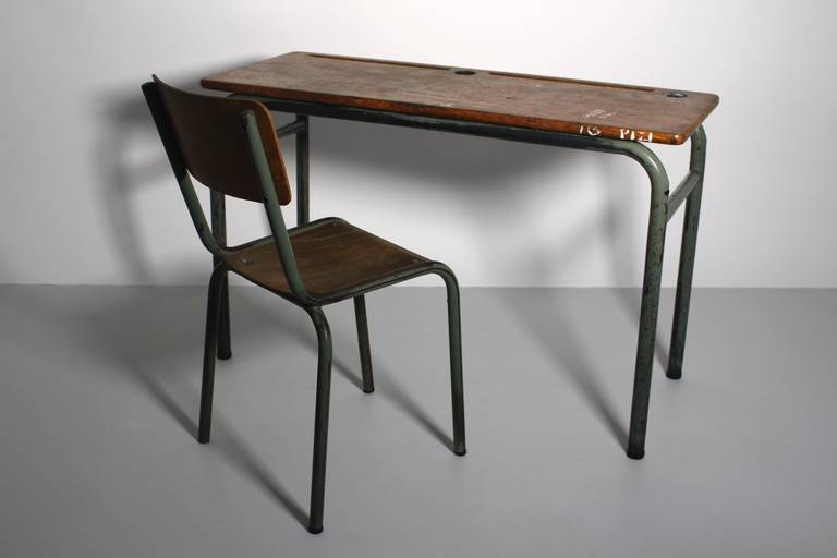 This presented charming French desk in the style of Jean Prouve includes a chair and was designed and manufactured circa 1940.
The desk features on the top of the plate old color spots and nice scratches. 
The metal frame was made of grey lacquered