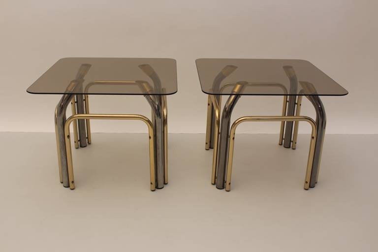 This presented pair of matching vintage brassed and chromed metal side tables were designed and executed in Italy circa 1970.
The base was manufactured of brassed and chromed metal and topped with a smoked glass top.
We offer these pieces as