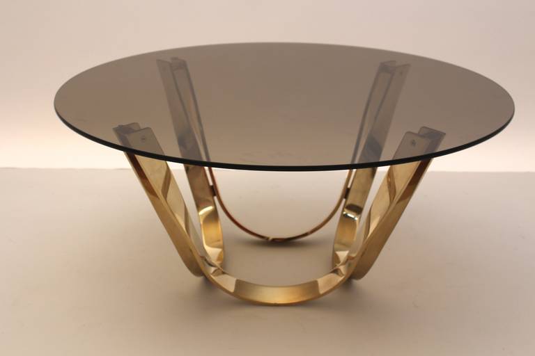 A mid century modern vintage brass coffee table by Trimark, in the style of Roger Sprunger for Dunbar, 1960´s
The brass base is formed as four ribbons with a smoked glass top. Very good condition with signs of age and use for both. 
All measures are