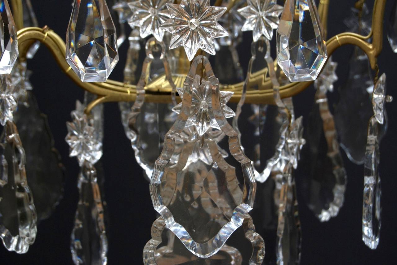 An exquisite Louis XV style French chandelier ''lustre cage'' with six light, richly festooned with beautiful crystal pendants, flower rosettes and stars.
With six candle arms and three cage arms.
The crown of the chandelier is supported by two