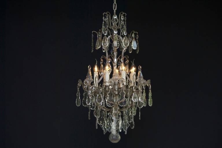 A fantastic silvered eight light French crystal chandelier, richly festooned with flower rosettes, various clear crystal pendants and octagons.
The chandelier has four cage arms and eight candle arms. Between the candle arms is an extra arm with a