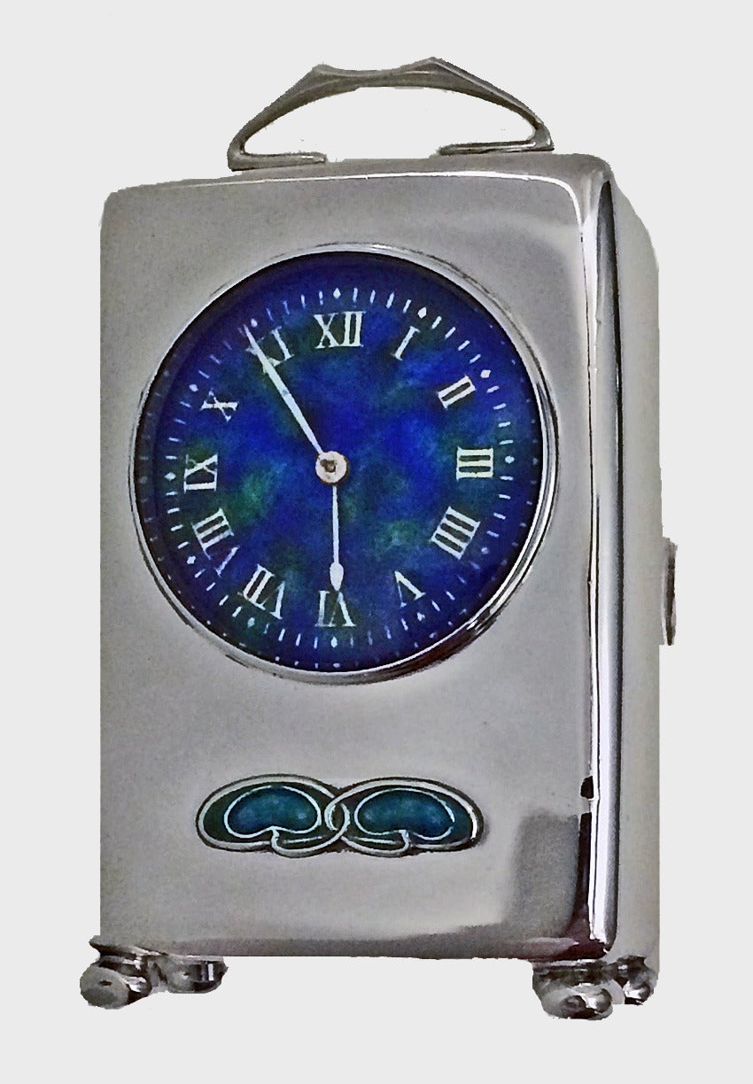 Liberty & Co, 1909 silver and enamel carriage clock. The clock of rectangular form, the front with stylized leaf motif in blue and green enamel and enamelled dial with numerals, on ball feet. Height: Excluding handle 8.0 cm. Stamped 'L&Co' with