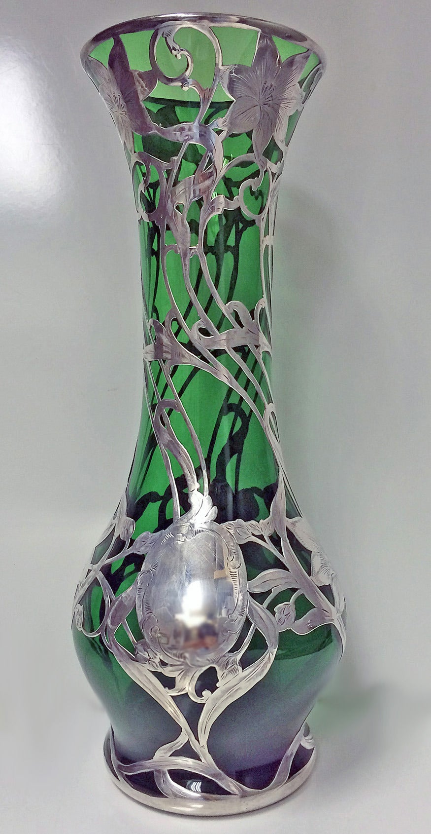 Large Art Nouveau emerald glass vase with sterling silver overlay. Made by Alvin, providence, circa 1900. The vase of slightly bulbous tapering form, everted rim. Thick applied silver overlay in form of lush and open blossoms with whiplash stems and