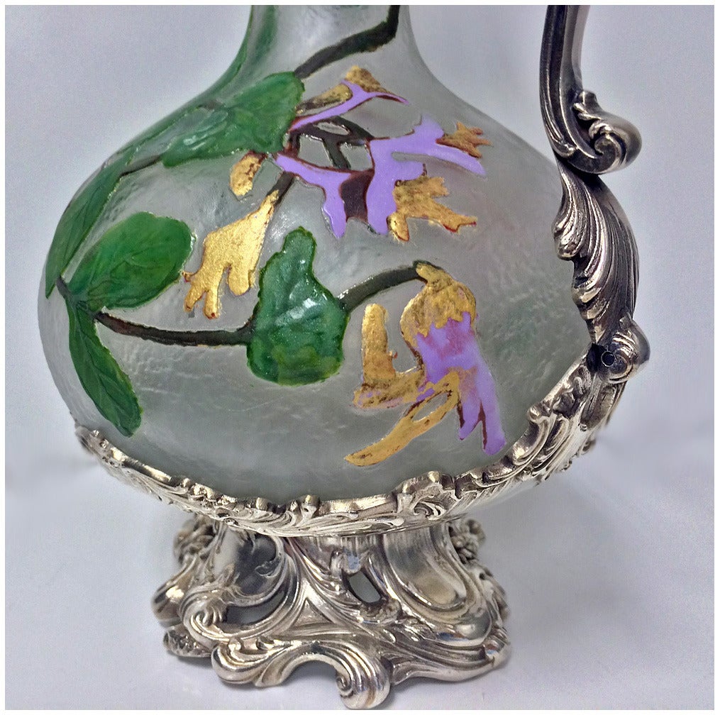 Art Nouveau WMF glass hand-painted Claret jug, circa 1900. The Claret jug with frosted acid glass, hand-painted enamel floral design in organic Art Nouveau style in green, lavender and gold tones. The Claret jug of bulbous form with elongated