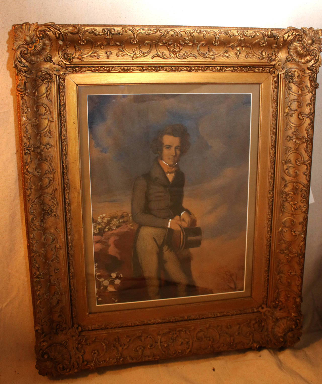Well executed pastel featuring an English gentleman wearing early 1800s Regency style attire painted against a background of soft pink and blue clouds. Unsigned.
Matted in heavily carved gilded wooden frame. Lots of detail.