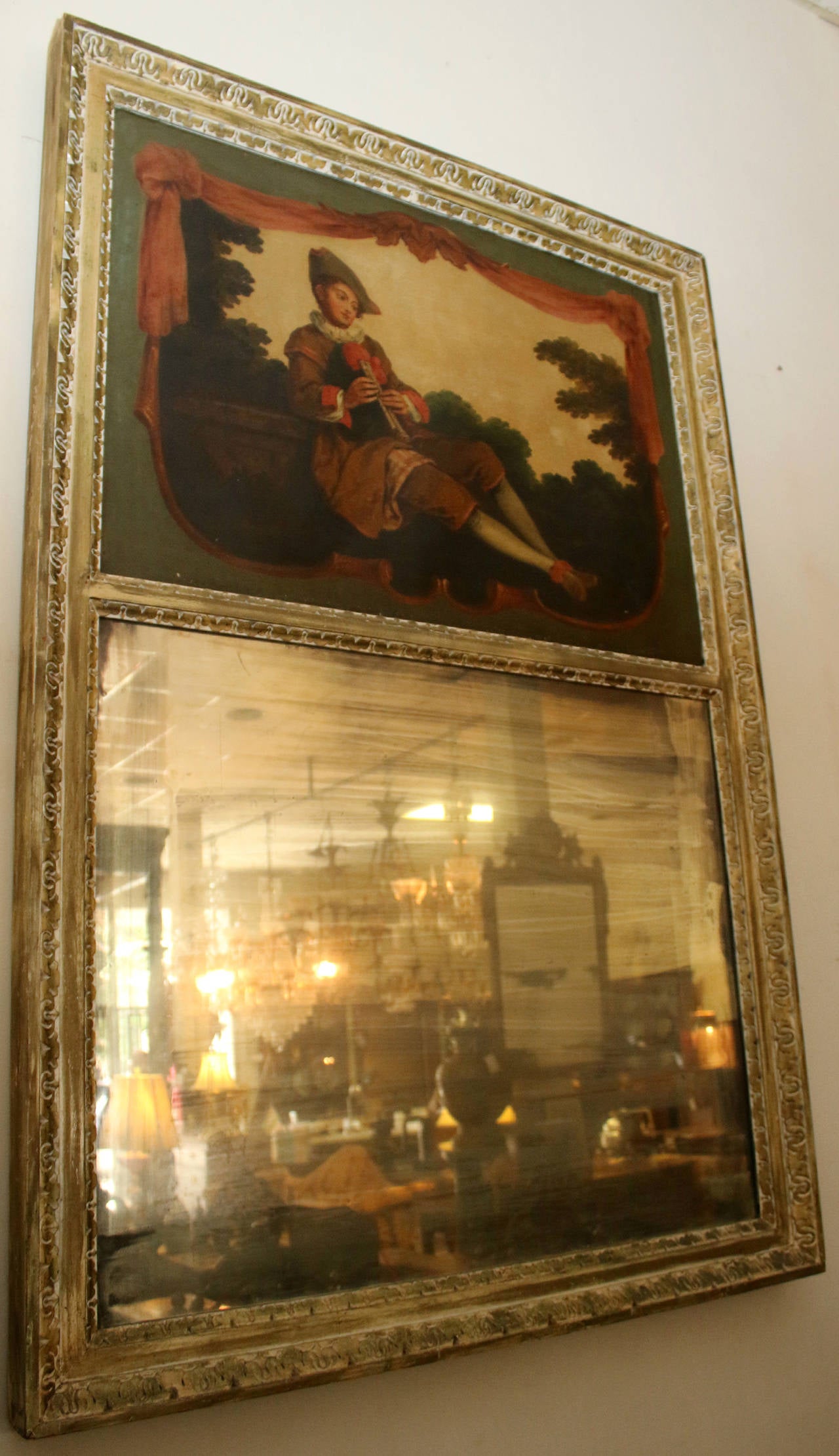 Miroir Trumeau français de taille impressionnante, de style Louis XVI, datant du début des années 1800. La peinture à l'huile sur toile représente un musicien en tenue de cour, un jeune homme jouant de la double flûte dans un cadre pastoral. La
