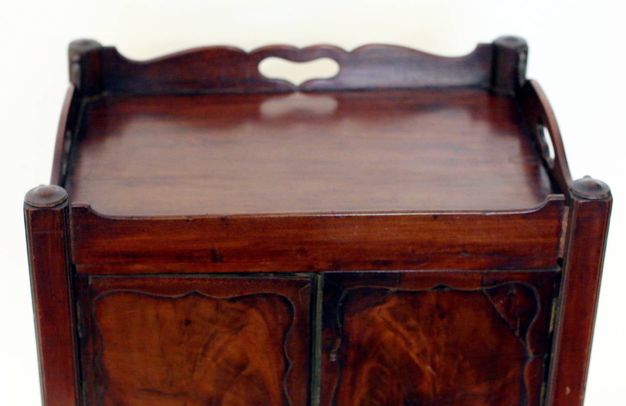Georgian period mahogany English bedside table commode featuring a full gallery top with pierced handles and two-paneled cupboard doors above a single deep commode drawer on square legs.
See measurements below.
