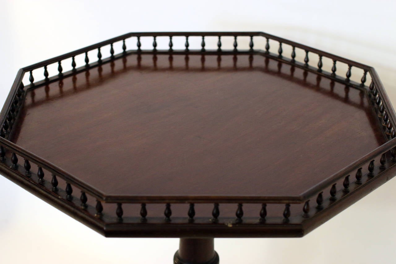 Mahogany tilt-top English tea table featuring an unusual octagon shaped tray with turned baluster gallery supported on a tripod base with slightly flared legs. Carved with leaf decoration on legs and feet. Working mechanism. See measurements below.