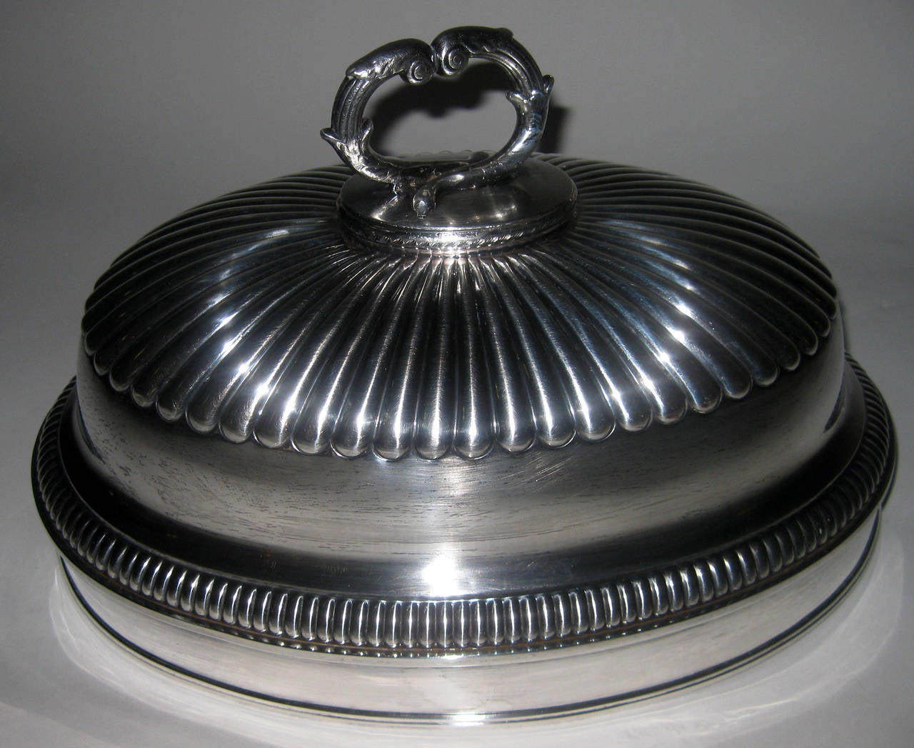 Large size English silver plate meat or food dome featuring extensive ribbing, a graceful twig motif handle and a crown engraved armorial. The initials RHC are distinct but the Latin phrase is very faint. The number 55 is marked underneath. See