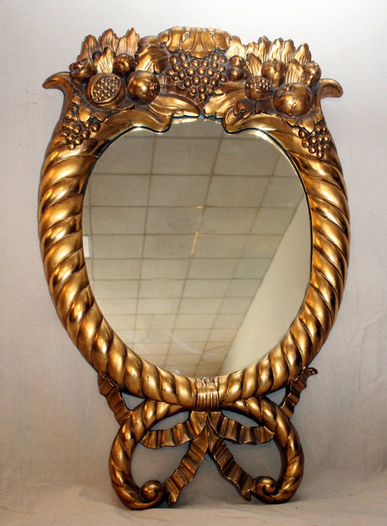 Richly carved, this American Empire style mirror is delicate yet it has commanding presence. The combination of classical elements does not repeat any conventional European designs of the period and thus speaks of an American origin. During the