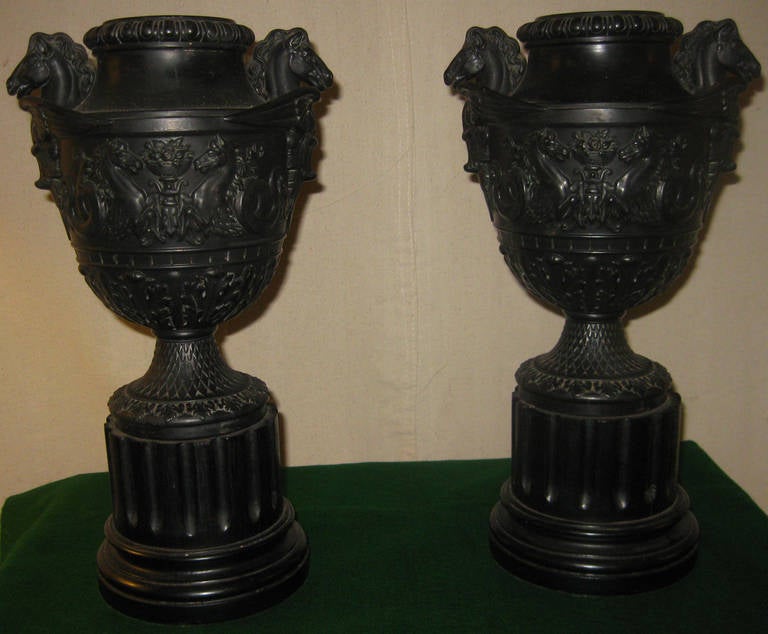 Pair of English Neoclassic style Jasperware basalt urns with Pegasus handles. From Greek mythology, two Hippocamp between an urn with flowers are the focal point on the front of the urn, with acanthus leaves tapering down from there. The body is