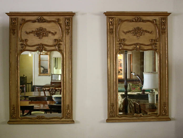Pair of 19th century French Louis XV style trumeau mirrors made of gilded fruitwood. Features include intricate hand-carved applique in a decorative floral design and rocaille stylized scroll work. Nice large size with original gilt finish and