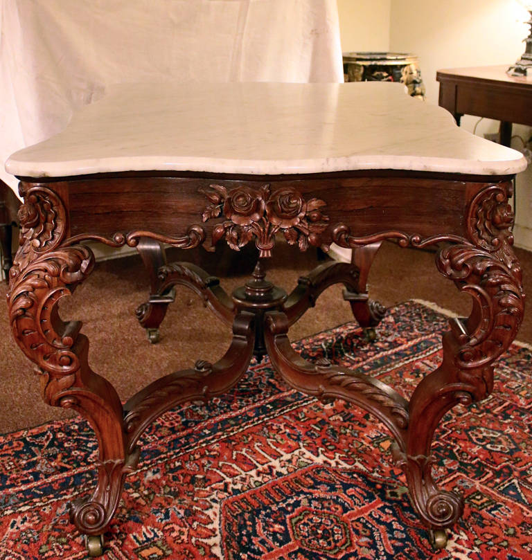 Center table attributed to the prestigious New York firm of Joseph Meeks. Heavily hand-carved rosewood featuring floral bouquets and rosettes, graceful serpentine legs, fanciful stretchers and beveled white marble top. See measurements below.