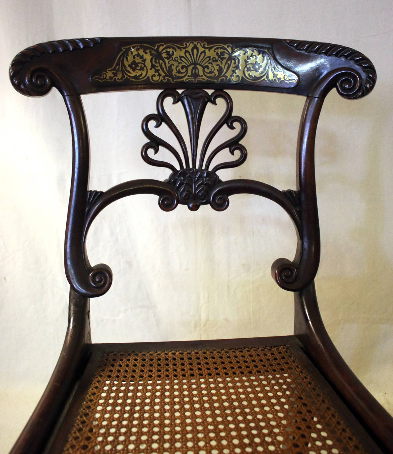 Pair of early 19th century Regency mahogany chairs featuring inlaid Boulle marquetry and caned seats. These are museum quality and are suitable in an entry or a special place with light usage. Very graceful serpentine backs. See measurements below.