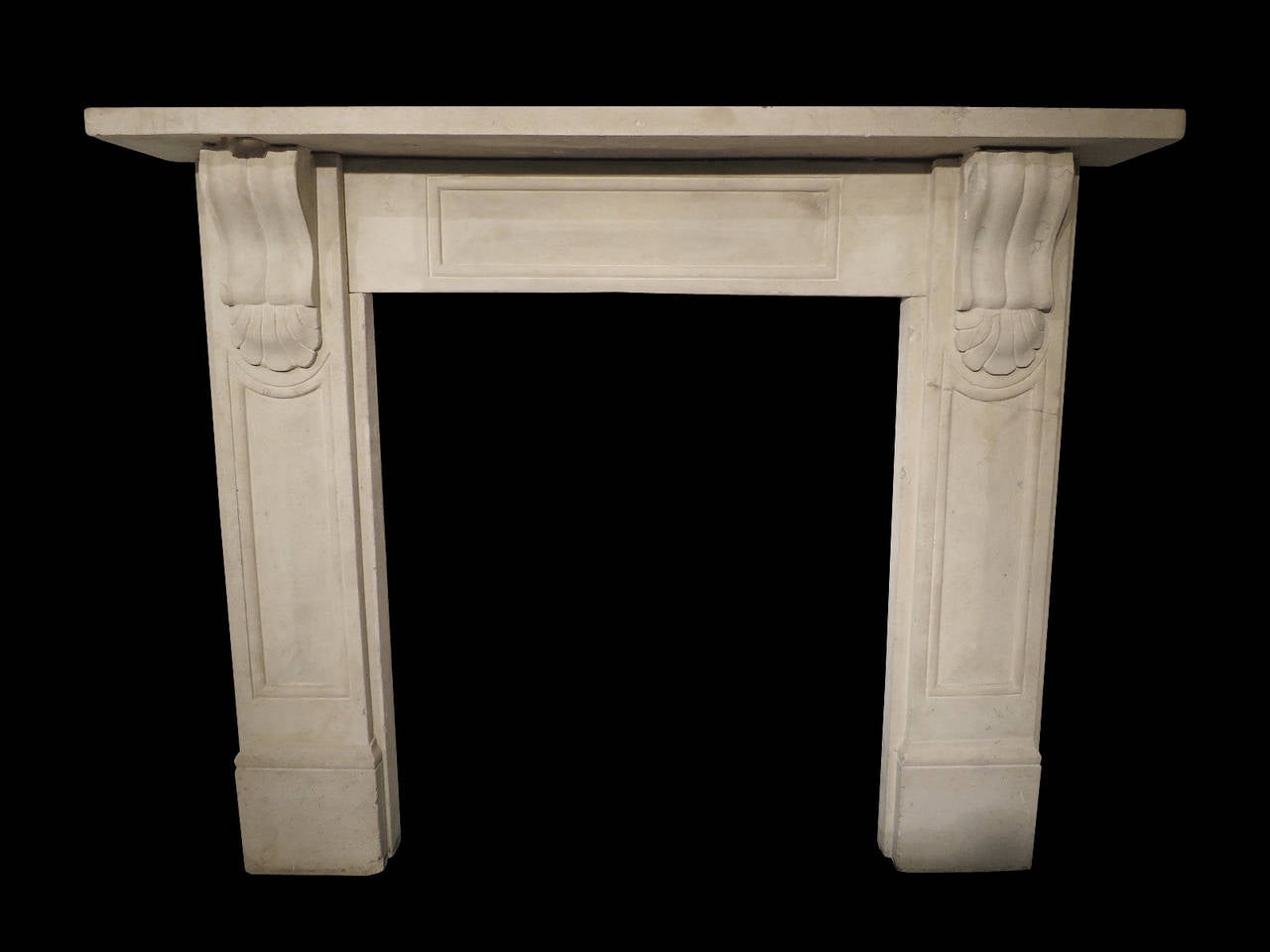 An English limestone fireplace, with raised panelled jambs and matching frieze. Carved corbels with unusual shells and plain mantel. Mid-19th century Victorian stone surround.