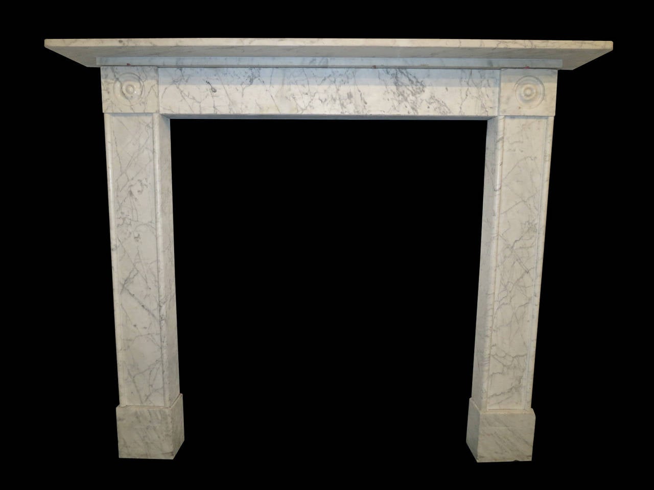 A very late 18th or turn of the century fireplace in pencil vein Carrara marble. Having typical characteristics of the 18th century with deeper inside returns solid marble foot blocks and stone backed jambs and frieze. The inverted panel jambs
