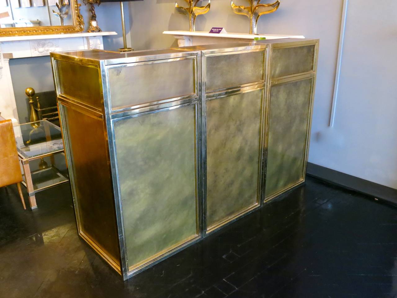 A three piece bar which can be configured into several shapes, with gold lacquered edging around distressed bronze brass coloured panels. The rear of the bar with plenty of storage and removable shelving. Each pieces dimensions are 120cm high x 60cm