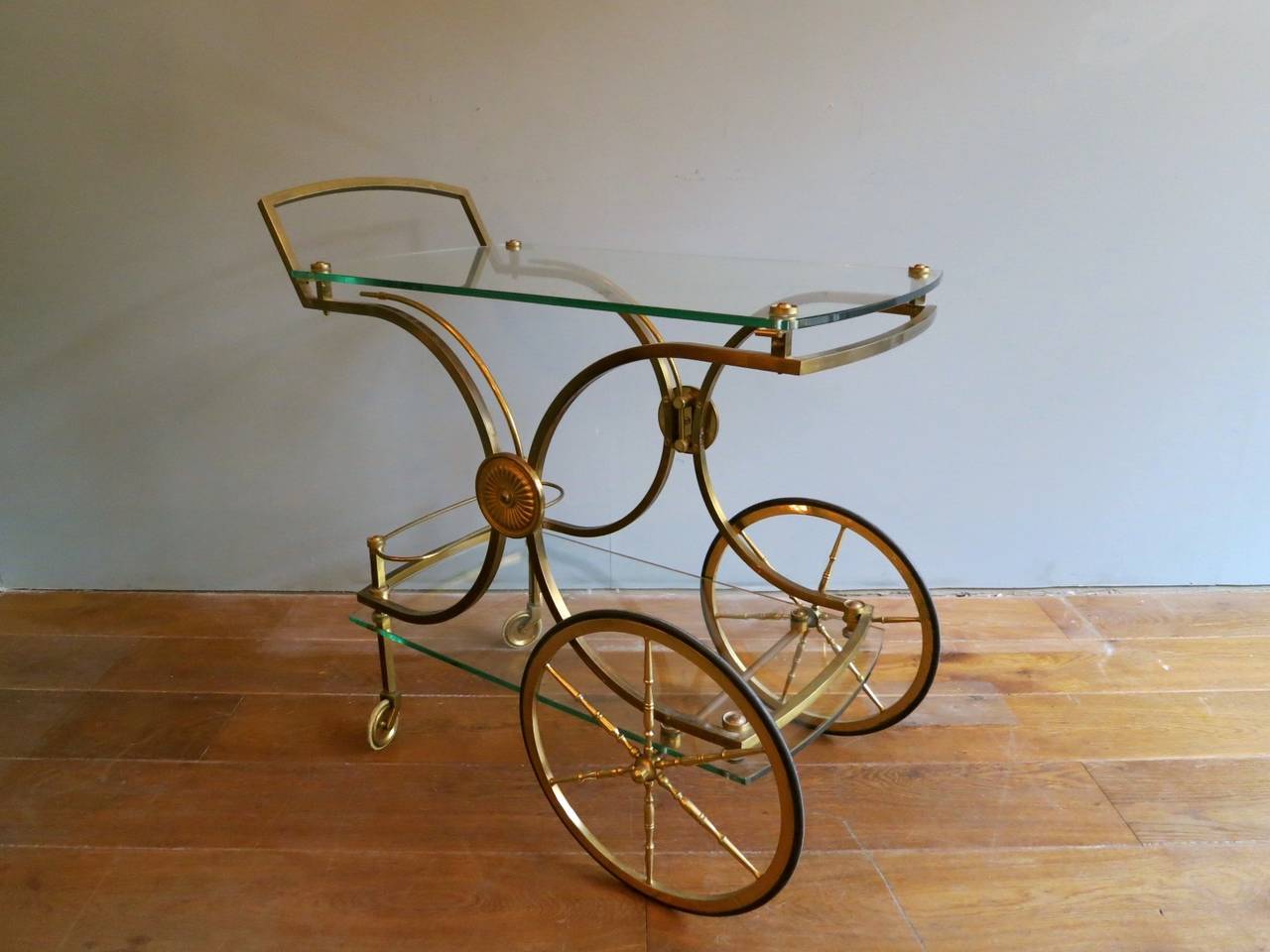 A very good quality brass and glass cart or trolley. A brass X-frame design decorated with brass rosettes supporting two glass tops. There are two supports which swing out for further use. An elegant and superior cart.