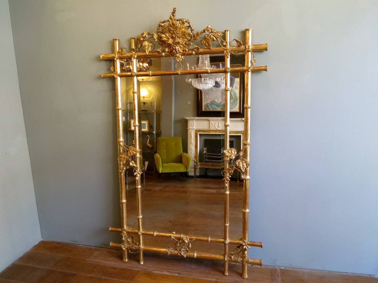 A large paneled gilt faux bamboo mirror, with ornate top cartouche of foliage and flowers. The frame intwined in gilt vines and leaves. The original plate mirror in the centre is bevelled with some slight foxing of age. An unusual and very good