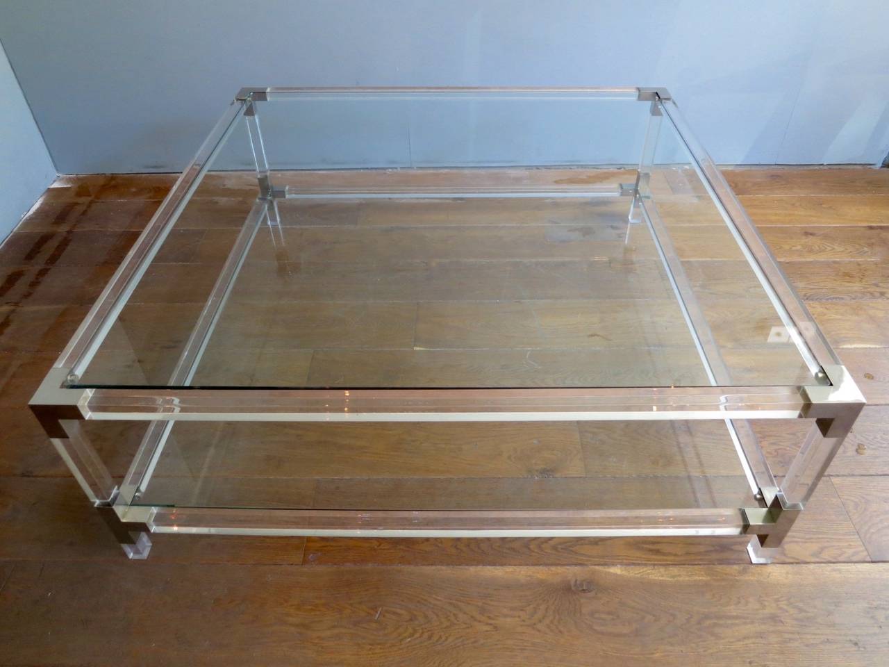 A large and low, two tiered French Lucite coffee table with polished nickel supports.