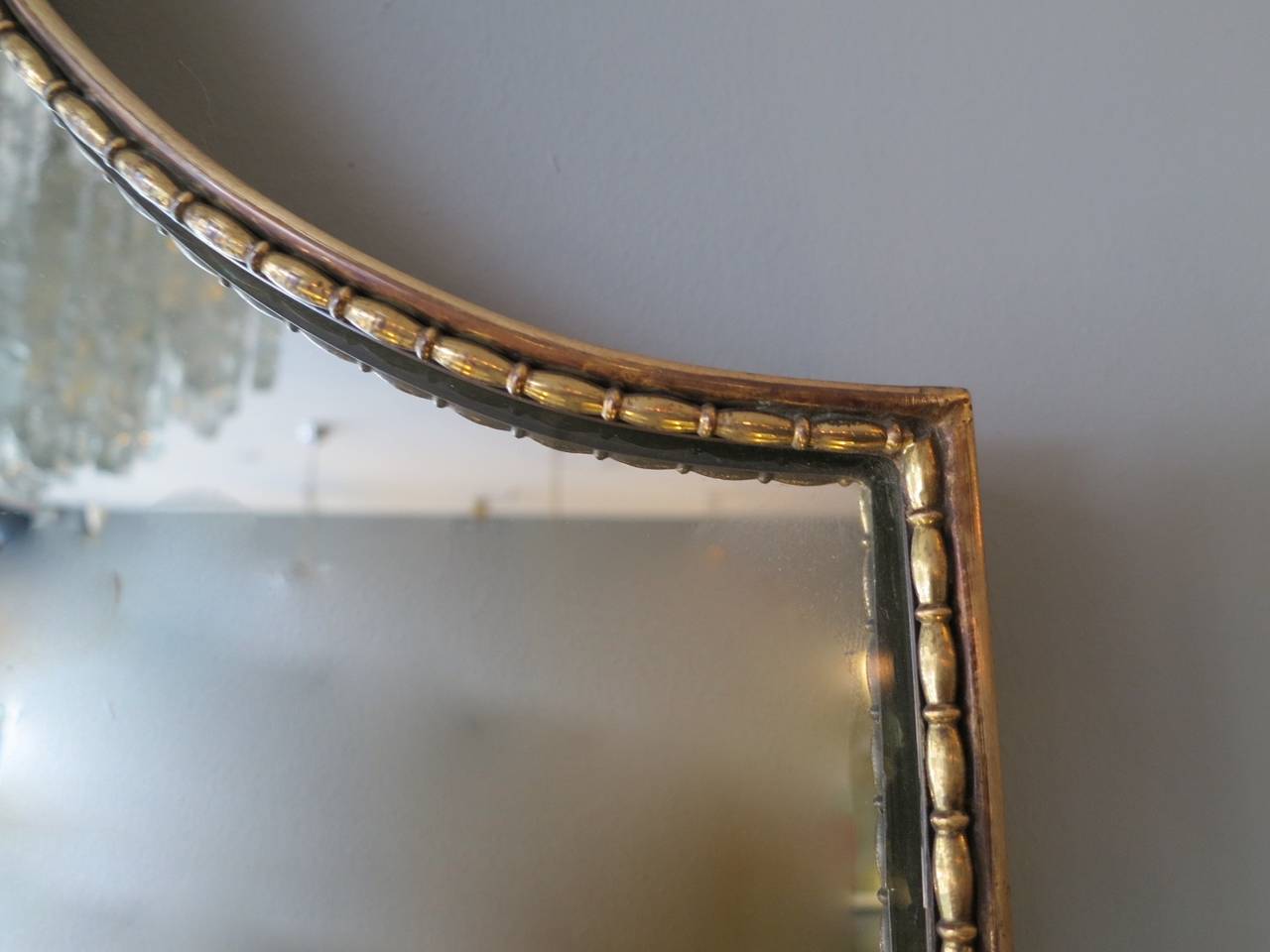 A brass shield shaped mirror with decorative beaded inner.