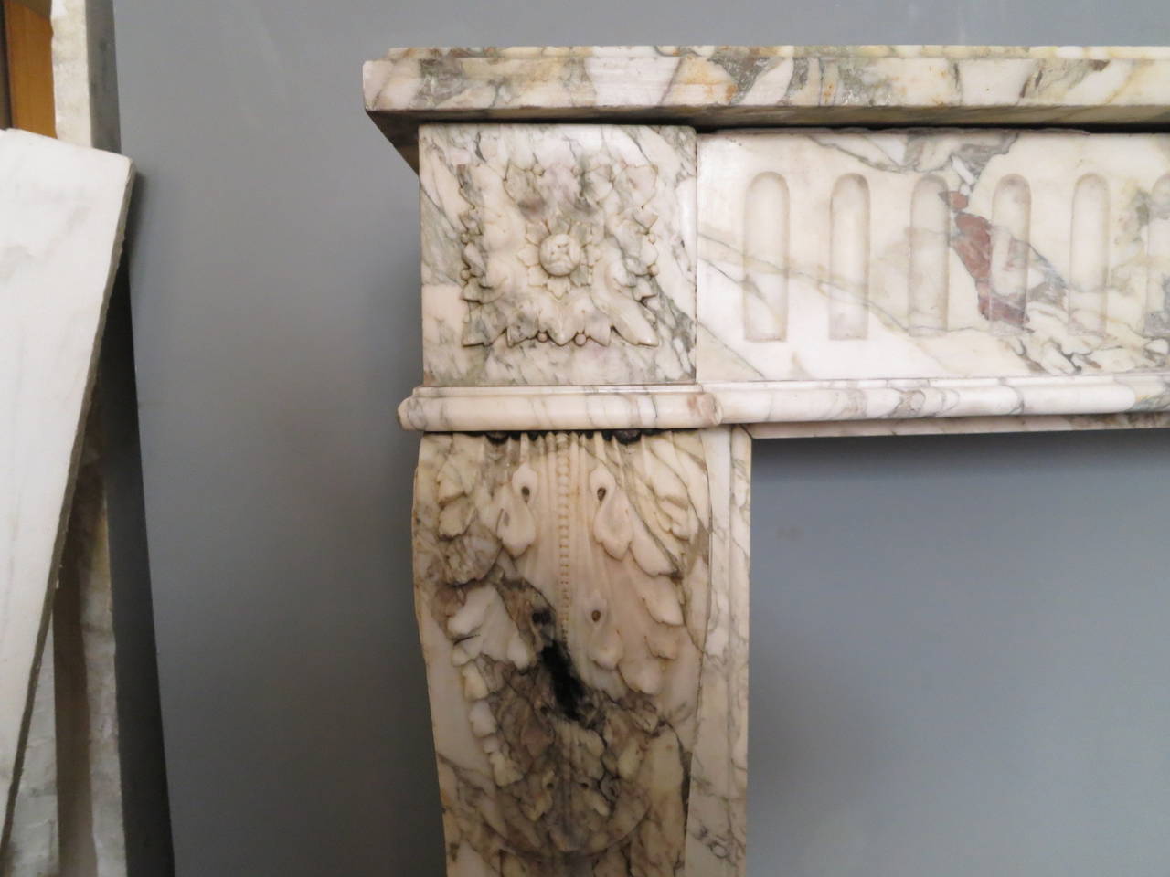 An early 19th century finely carved Louis XVI style fireplace in rare breche marble. The console jambs with tapering front panels and very well carved acanthus leaf with beading. The side returns paneled. The corner blocks of well carved square