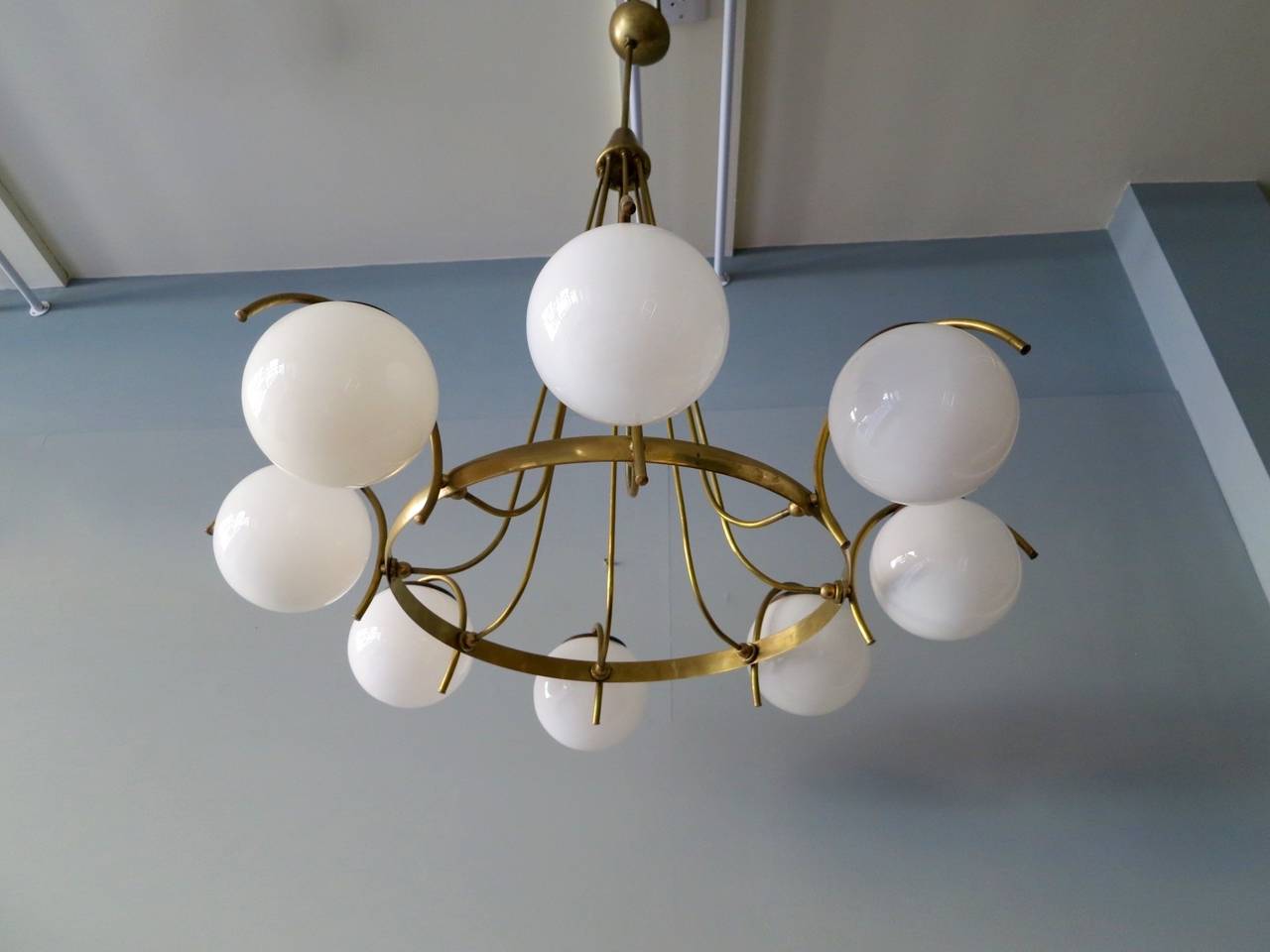 An eight-arm chandelier, with opaque glass diffusers suspended from a brass frame. Possibly by Lelli for Arredoluce. In its original state, can be re polished if desired.