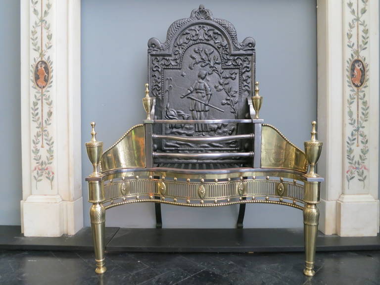 A large 19th century fire grate, with brass acanthus leaf engraved legs, engraved decorations on the wings and pierced fluted fret work decorated with oval paterae, classical urn finials and decorative cast iron back.