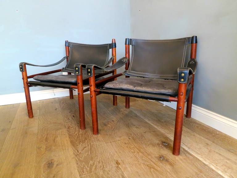 A pair of black leather and palisander safari chairs by Arne Norell, Sweden.