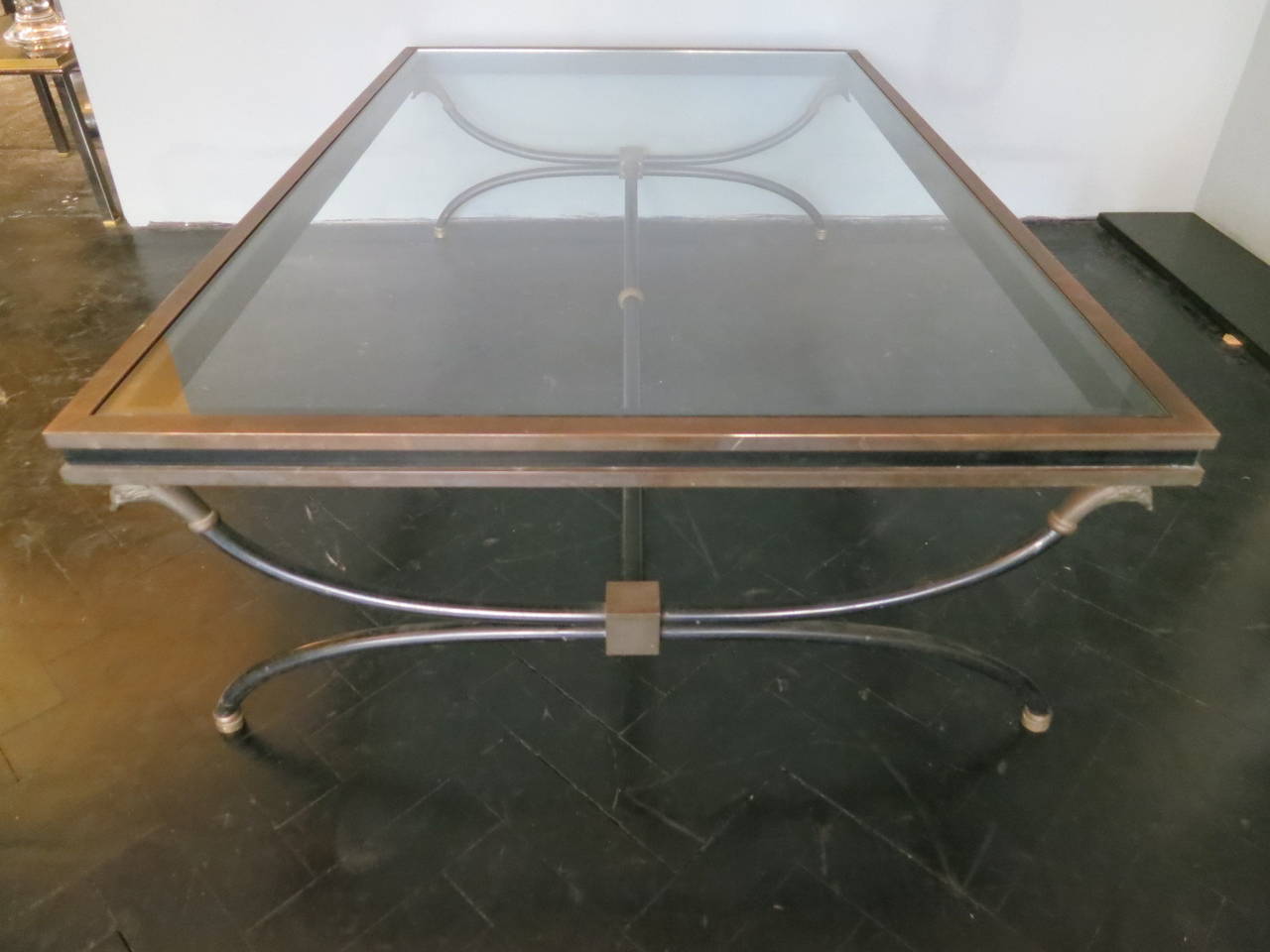 A large bronze and black steel framed neoclassical table with braze feet and birds head supports.