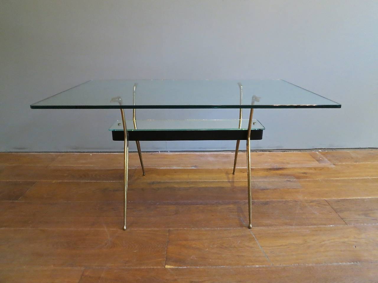 An Italian coffee/cocktail table by Cesare Lacca. Architectural style brass supports with a mirrored under tier and thick rectangle glass top.