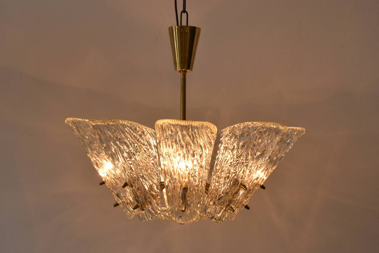 Impressive 1950s textured glass and brass chandelier by J.T. Kalmar, Vienna, Austria. Thick glass with different textures on the in- and outside creates a fantastic light effect. Nice brass bolts, eight bulbs.

Original condition.