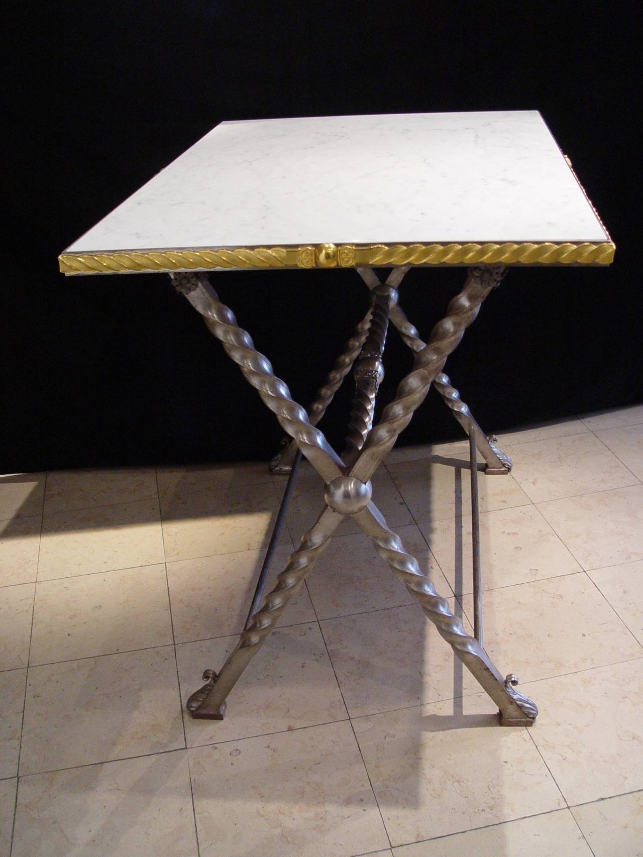 A wrought iron table with Carrara marble top,
consulate, circa 1800
gilded bronze belt around the top
Dimensions: W 41 ¾ in X D 29.5 in x H 36 in.

This table recalls the folding campaign tables under Napoleonic times, where army officers used