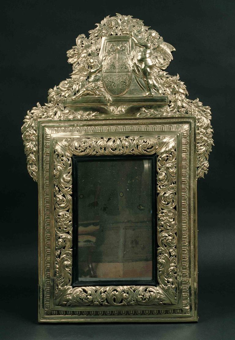 Flemish mirror in its brass frame with a decoration of blooming flowers and acanthus leaves.
It is made with a large single piece of embossed brass, with pieces of mirror inlaid in the wood.
The front is carved with two putti with widely spread