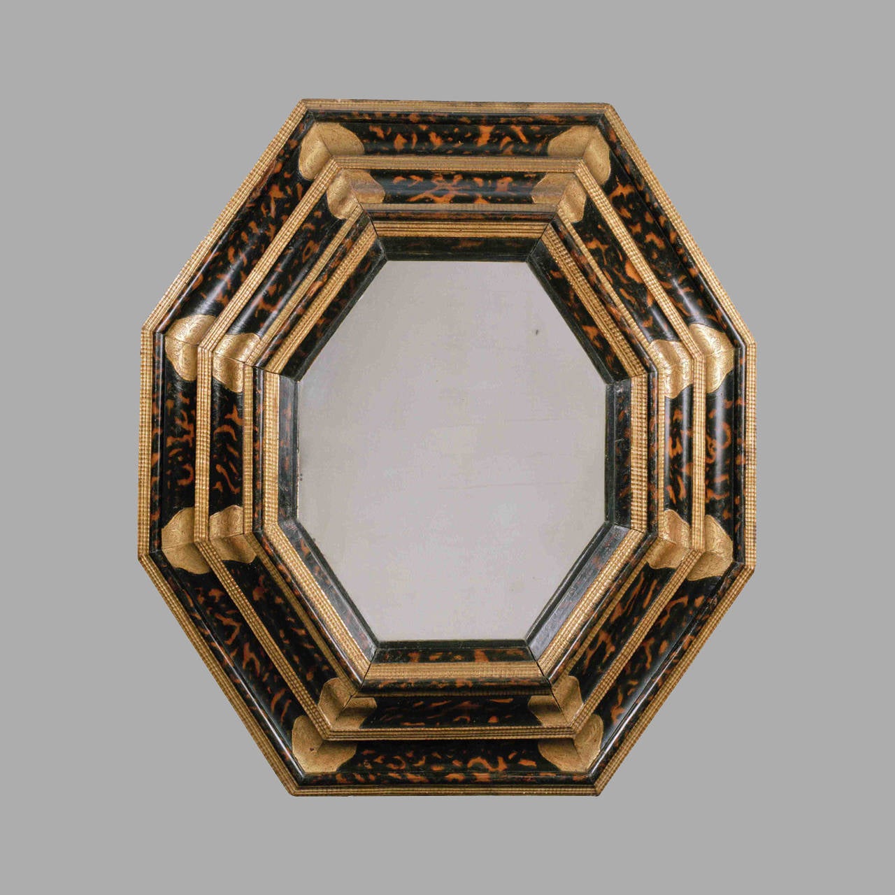 An octagonal moulded wooden mirror from Italy, Les Marches, late 17th century.

It has kept its original decoration in trompe-l’oeil
tortoiseshell, it has also kept its original engraved gilding.
The three superimposed levels reminds of the