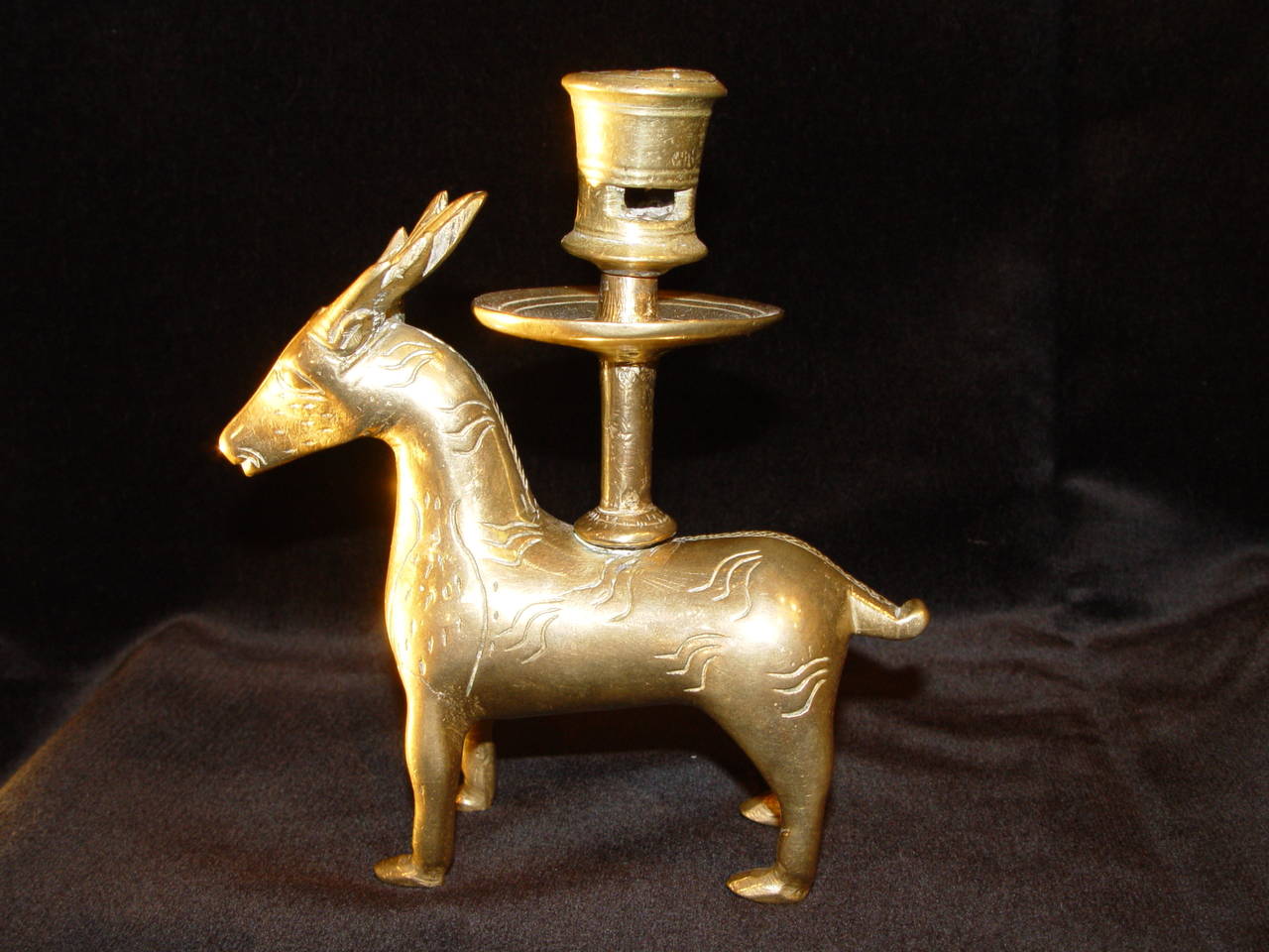 A SMALL YELLOW BRASS CANDLESTICK In shape of a deer
Mosan workshop- Belgium or Germany
 15th century

Yellow brass gothic zoomorphic candlestick, mounted on the back of a deer whose antlers are joined together, with a simple candleholder and