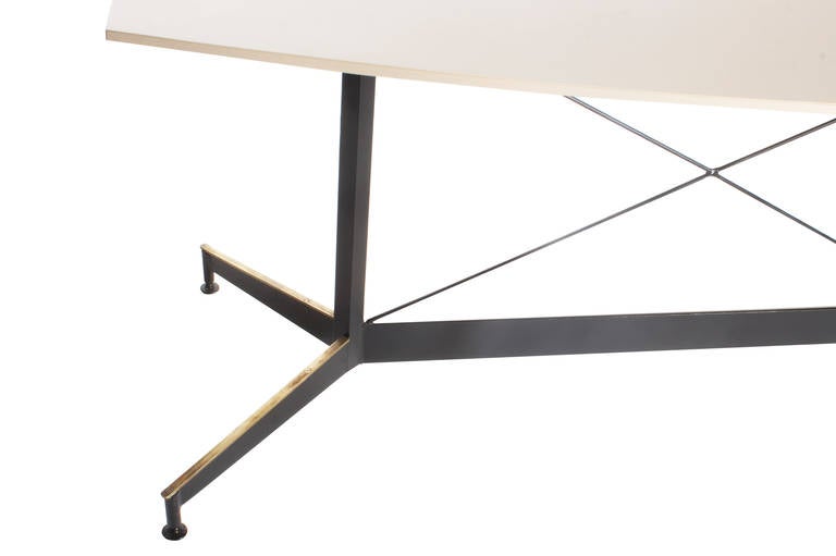 An off-white, hinting-at-taupe laminate top over a black metal base with X-configuration and aged-brass accents.

Beautiful representation of Italian Mid-Century.