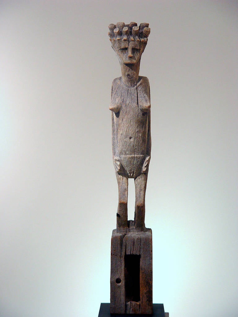 Female wood figure from Madagascar.
This sculpture of a woman originally adorned such a gravesite. Its bent knees, elaborate coiffure and full bosom emphasize an ideal of female imagery that was originally paired with a male figure to suggest