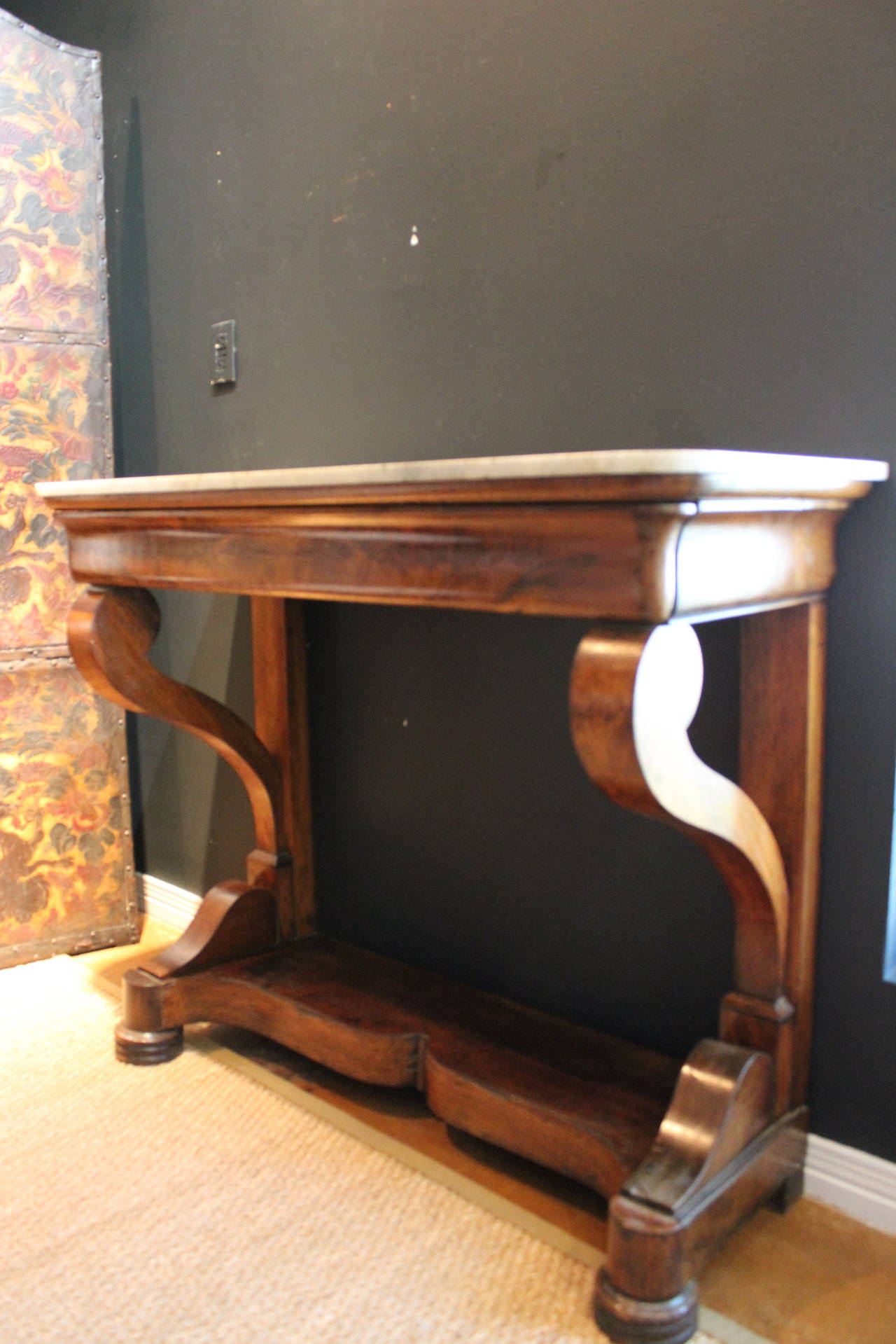 Antique walnut console table with scroll base and hidden drawer set below aged white and grey Carrara marble top.